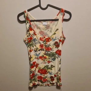 Blommigt linne  - Blommigt linne från ginatricot. Stretchigt och bekvämt material. Går att knäppa upp i bysten. Storlek XS men sitter bra på S. 