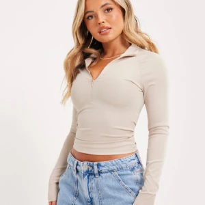 Half zip top - Säljer denhär zip toppen från Nelly som är slutsåld, kommer inte till någon användning tyvärr. Skriv privat för egna bilder!