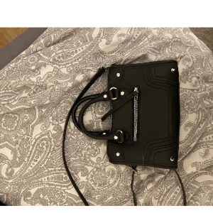 Svart väska - Säljer min fina och trendiga handväska med silver detaljer, jätte fin och rymmer mycket. Den är använd fåtal gånger så den är i nyskick! 💕 