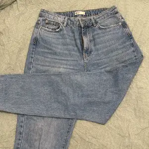 Jeans från Gina Tricot i storlek 38. Raka/ momjeans. I bra skick. Slitningsdetaljer på fickan och byxkanten. 