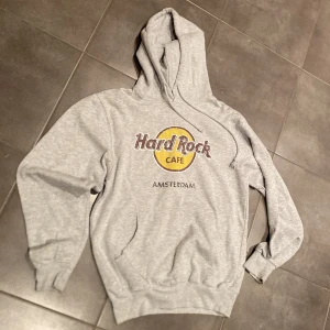 Hard Rock Café-Amsterdam, grå Hoodie, stl M - Hard Rock Café-Amsterdam gråmelerad hoodie, med tryck fram, fint skick, stl: M
