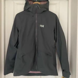 Helly Hansen skidjacka - Helly Hansen skidjacka stl M. Innerjackan sitter fast med dragkedja och går att ta ur. Gröngrå färg.