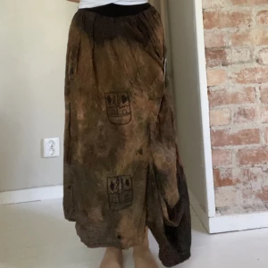 Långkjol - Cool, veckad långkjol! Köpt på loppis, vet inte märket. Kommer med en stor säkerhetsnål man kan sätta som man önskar för att styla den lite på olika sätt. Resår i midjan men den är lite slapp, men sitter ändå bra! Står ingen storlek men skulle säga M/L. 