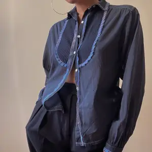 beautiful vintage women’s tuxedo shirt, hand dyed vintage in navy blue color  lace trims and pleated front details  puffy, cuffed sleeves for feminine effect with white button closure  unique piece, some natural dye discoloration & a tiny pinhole in left 