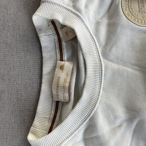 Vit tröja - Riktigt skön långärmad från scotch & soda. Tröjan har ett riktigt nice tryck på ryggen som ändrar färg när man går ut i solljus. 