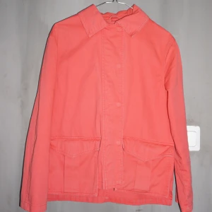 Korallfärgad jacka  - Jag säljer denna pärla som köptes för några år sedan på ASOS. Jackan är i gott skick förutom fläckarna på kragen och bröstet som visas på bild 3. Den passar perfekt för våren och hösten och bidrar med en färgklick i vardagen.