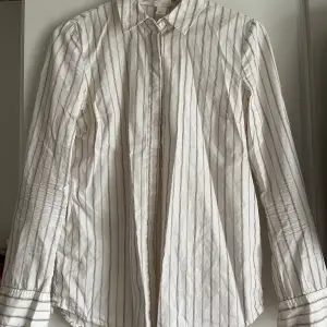 Figursydd beige skjorta med lila ränder från HM x Giuliva Heritage.  Smäcker och ger ett ”dressat” intryck, men kommer tyvärr inte till användning hos mig. Passar xs-s. Är tyvärr inte struken vid försäljning. 