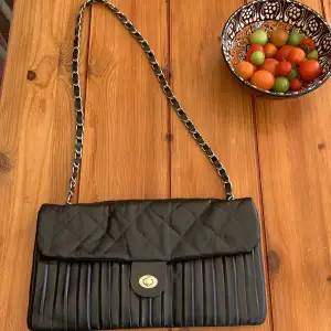 En svart handväska med kedjerem och två fack 