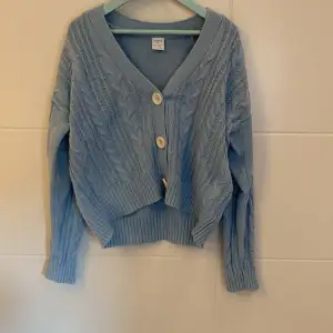 En blåa tröja/kofta med vita knappar, säljs för att den inte används (hon som bär tröjan är 163-164 cm)👌🏼❤️