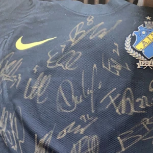 Aik match tröja signerad av aik spelare. Jag är inte säker på vilka signaturer de är ifrån men jag vet att Alexander Isak signatur är med där. - Det är inget nummer eller namn på baksidan den har inte varit använd av en fotbollspelare. Jag fick tröjan av Erik ring. Nu vill jag kolla hur mycket den är värd. 