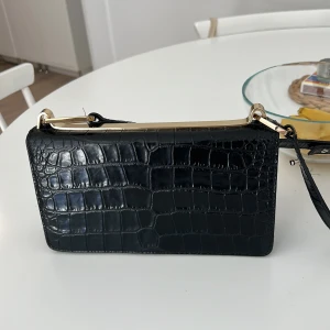 VÄSKA - Snygg svart väska med guld detaljer frön &other stories. Knappt använd. 