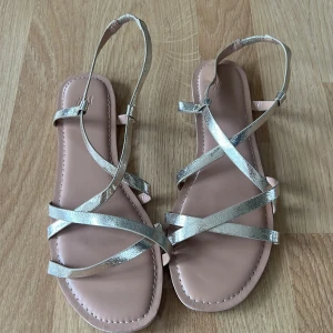 Sandaler  - Fina sandaler får hm med guld omlott band. De är i storlek 40 men är väldigt trånga jag har 39 och säljer för att de är på gränsen för mig💖 användna endast 1 gång