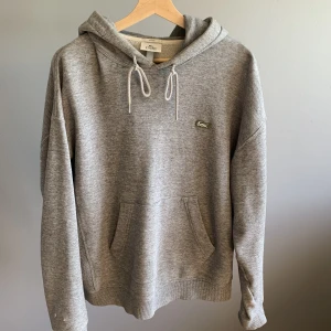 Lacoste Hoddie - Säljer en sparsamt använd hosdie från Lacoste. Två mindre hål vid höger handled, men inget som stör.