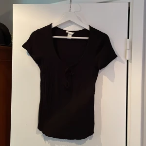 Svart T-shirt med knyte - En svart topp från HM men snörning fram. Knappt använd!