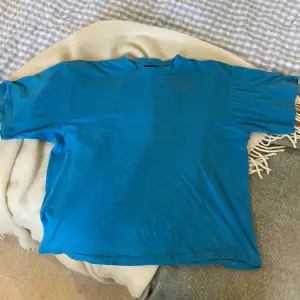 En blå oversized t-shirt i storlek (XL) MEN den är croppad så skulle säga att den nu är storlek M! Fint skick men har en liten fläck, se andra bild