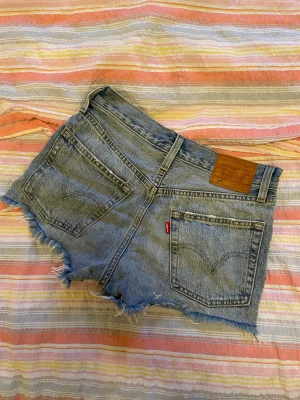 Levis shorts w24 - Blå, korta jeansshorts från Levis med slitningar, köpta i New York och använda väldigt få gånger. Storlek W24