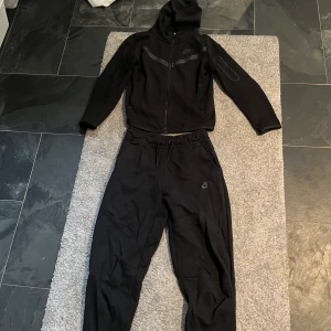 Svart Nike tech fleece set - Ett super snyggt svart Nike tech fleece set i storlek M i barnstorlek, passar mig 16 åring tjej 165 cm. Säljer pga ingen användning av längre. Använt 1 gång, så nästan som ny!