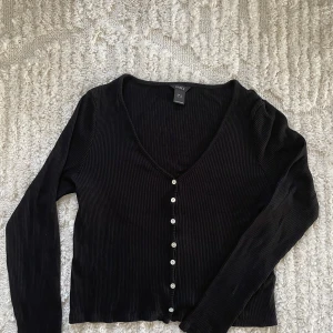 V-ringad topp - Svart v-ringad topp med knappar från Lindex. Storlek M. Nyskick, använd en gång.