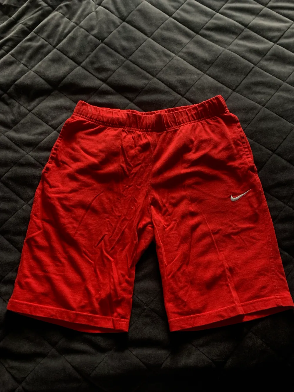Röda mjukisdjuret från Nike. Storlek small herr, lite lågmidjad modell. Ficka baktill. Små fläckar på bandet som kanske går bort i tvättmaskin, se bild 3, annars bra skick. 100kr+frakt. Shorts.