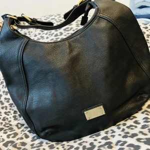 Dam axel väska i skinn - Dam axel väska i skinn.  Axelrem finns ej (kan köpas och användas)  Färg: svart skin.  Innre och yttre fack finns.  Ej använd