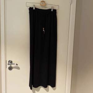 Säljer en mörkblå/svart kjol med jätte fina snören med färgglada pärlor på, helt oanvänd men förliten