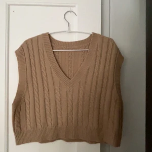 Stickad väst  - Beige stickad väst i lite kortare modell. Superfin att ha över en skjorta eller bara precis som den är. 