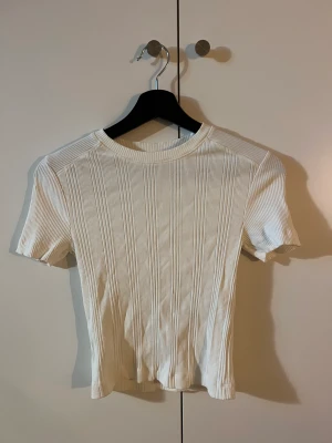 Vit T-shirt  - Vit T-shirt från zara med ribbat mönster.  Storlek s sitter väldigt tajt och fint på kroppen. 