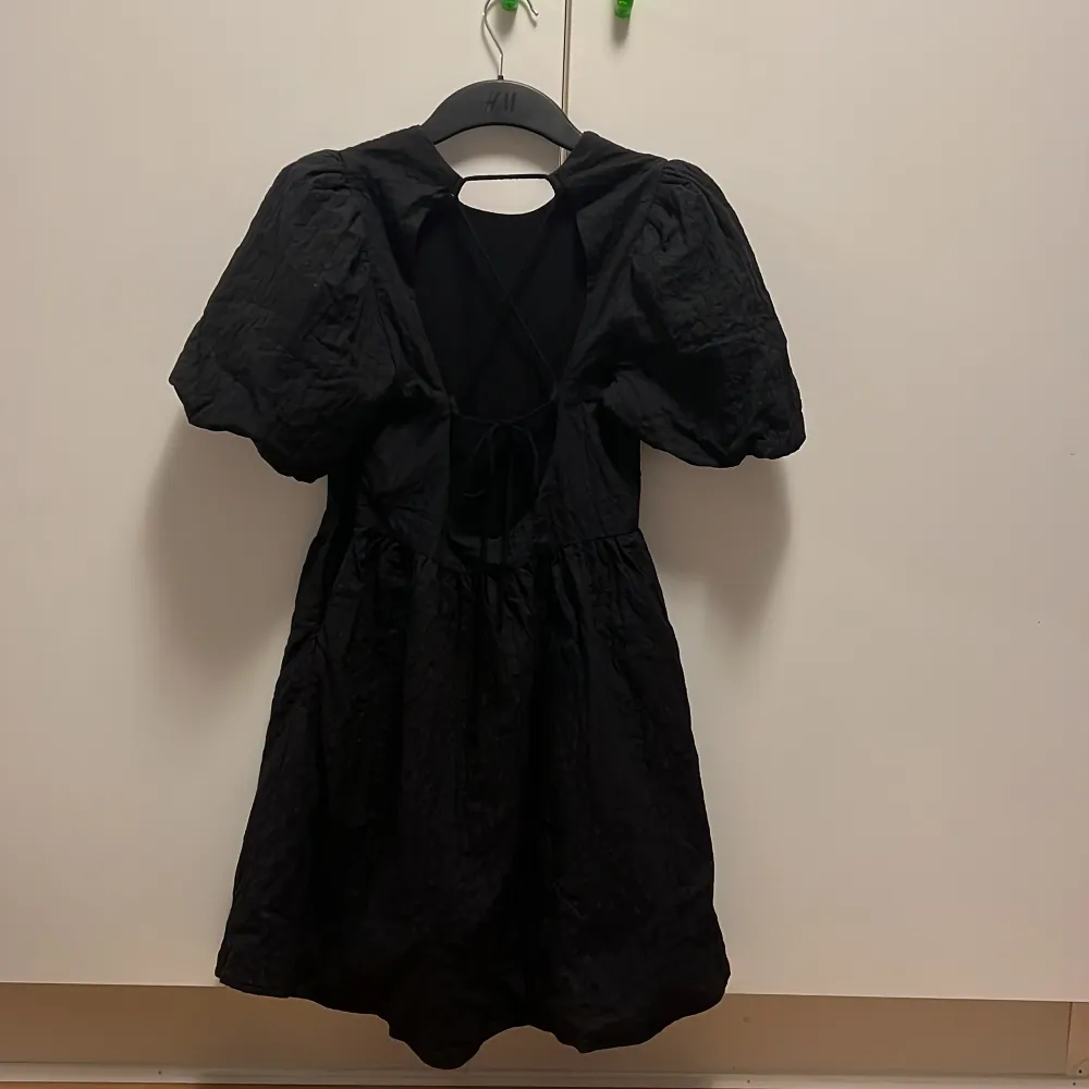 Superfin puffig svart klänning med öppen rygg med snörning. Perfekt längd, jag är 174cm lång. Ganska tjockt material men har aldrig tyckt att den är för varm. Kan användas både på sommaren och hösten/vintern med ett par tights💕 Strl 34 men sitter som 36😊. Klänningar.