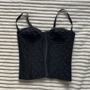 Korsett svart - En jätte fin svart korsett med vackert mönster i spetsen. Justerbara axelband samt en jätte fin knytning i ryggen! Endast använd 1-2 gånger. Skulle säga att de är en small 
