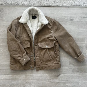 Manchesterjacka  - En brun manchesterjacka i 90-talsstil. Inte så lång, går ner till höfterna ungefär.