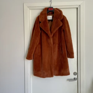 Fuskpäls  - Knappt använd. Rostbrun, knälång.