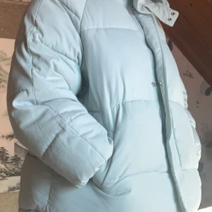 ljus blå jacka - blå jacka köpt från yesstyle. Är inte så varm, bra för hösten och våren. Har en luva som man kan knäppa så att man skyddar huvudet bra för vinden. armarna når precis så de är lite korta.