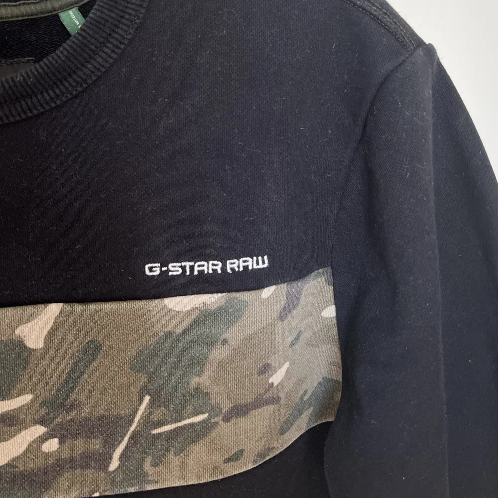 En herr sweatshirt från Gstar Raw, använd men i väldigt bra skick! I storlek M, den är svart med camouflage mönster på bröstet. . Hoodies.