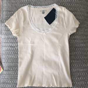 Brandy Melville topp - Så söt topp med spets och en rosett där fram. Aldrig använd!! Köpt från brandy melville, onesize. Pris kan diskuteras💕