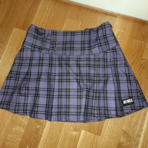 Plaid Mini skirt från Minga London - En lila rutig kjol med säkerhetsnålar från Minga London. Storlek S / 36. Har aldrig använts då storleken blev fel, prislappen sitter kvar.
