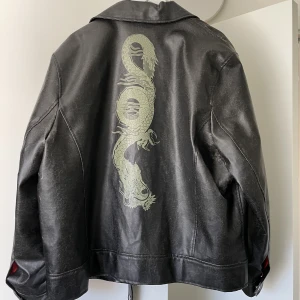 Vintage skinnjacka med drake på 🐉  - SÅ snygg jacka med drake på. Men kan inte ha den, för stor för mig :( Så måsta sälja den. Vintage slitning men inga andra defekter. 61 cm från axel och ner till midjan. 68 cm från axel till ärmens slut. Frakt: 109 kr 💚