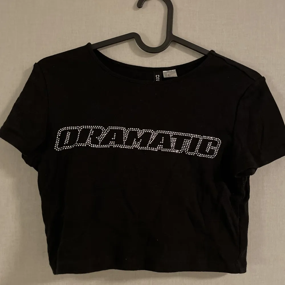 En svart croptop från H&M där det står DRAMATIC på😋 Aldrig använt den så den är som ny! Kontakta mig om ni har frågor <3. T-shirts.