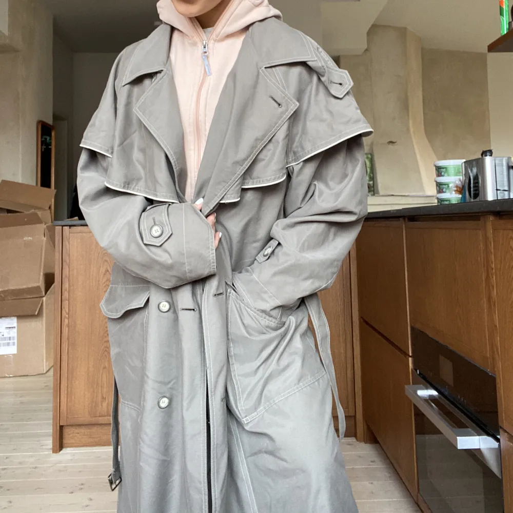 Supernsygg lyxig trenchcoat med månha fina detaljer, en gammal Kappahl. Den går ner till fötterna på mig som är 160cm. Lätt i materialet, perfekt till våren och sommarkvällar! Grå-grön/dusty green färg!. Jackor.