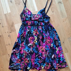 Sommarklänning - Fin sommarklänning i skönt material. Blommigt mönster med svarta axelband. V-ringad och skön att ha utan BH (tycker jag😁) Fick av en bakant för länge sen så vet inte märket. Stretchig över midjan och brösten.