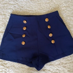 Eleganta short med guldknappar - Eleganta short i fin blå färg och guldknappar. Knappt använda så i nyskick! Storlek xs