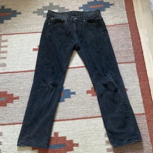 Levis 505 - Ett par svarta Levi’s 505 i bra skick utöver ett litet hål på högra knäet. Midja är storlek 34 men passar bra på mig som har storlek 30