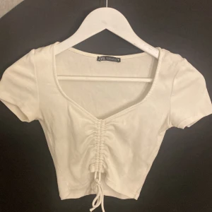 Vit topp från zara - Jättegullig liten topp från zara som knappt är använd. Mjukt material och justerbar i ”urringningen” med dragskon. Säljer då den blivit för liten och bara ligger o tar plats. Frakt ingår!!!
