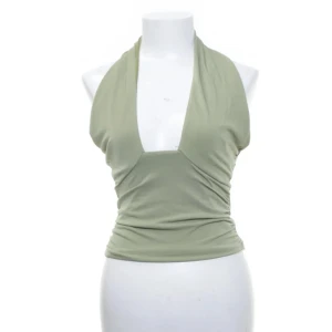 Grön halternecktopp - En grön/olivfärgad halternecktopp från bikbok. Toppen är relativt använd men inga större defekter. Den är bekväm och sitter på plats & passar perfekt nu till sommarn, festligare tillfällen men också casual till vardags men har dessvärre tröttnat på den. 