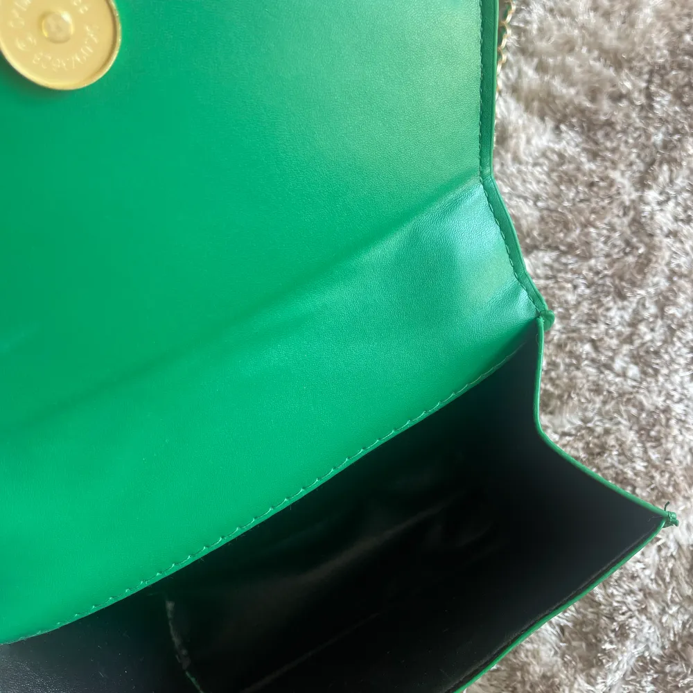 Oanvänd grön handväska med gulddetaljer. Väskor.