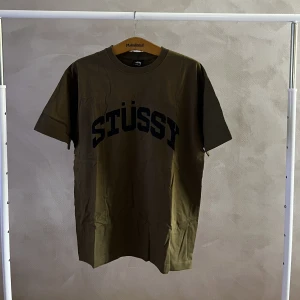 Stussy tröja - En grönbrun stussy tröja med vintage look och ett stort stussy tryck på bröstet Storlek large.
