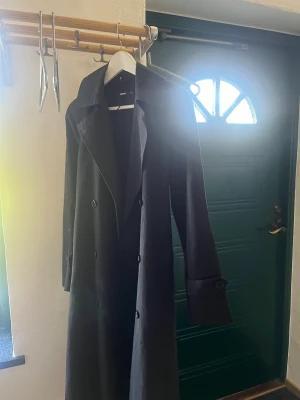 Trenchcoat  - Svart trenchcoat med midje band. Snygg använd 1 gång. Jätte skön och användbar. Ny pris: 1000kr
