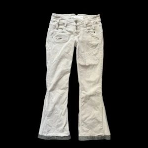 Beige lågmidjade jeans - Beige jeans/byxor med super nice detaljer och knappar. Midjemått tvärs över: 36,5 cm - Innerbenslängd: 75 cm