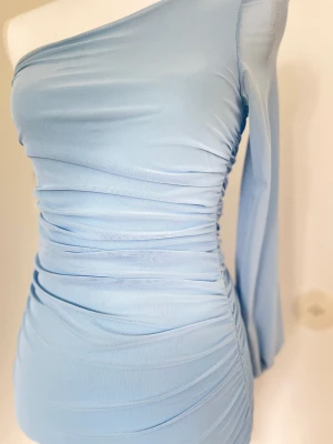 Blå festklänning - En jättefin blå tajt festklänning med superfina detaljer. Passar perfekt till en utekväll eller någon hemmafest/ födelsedagsfest. Används två gånger (tvättad)