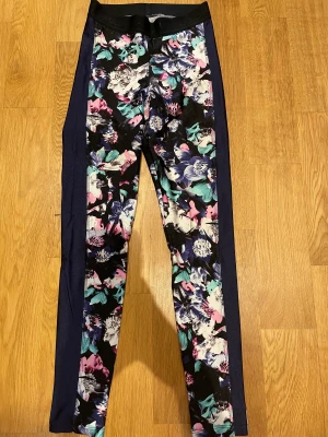 blommiga träningstights - Jättefina blommiga träningstights med mörkblå rand på sidorna. De är i nyskick och jag säljer dem pga att de är för små. Jag köpte dem för ca 800kr. Priset kan diskuteras 