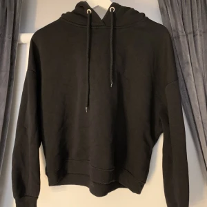 Svart hoodie som är ganska kort i modellen - En hoodie i nyskick. Endast använd fåtal gånger.